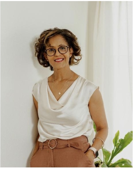 Portrait of author Azeb Melaku, smiling, wearing glasses and a cream blouse